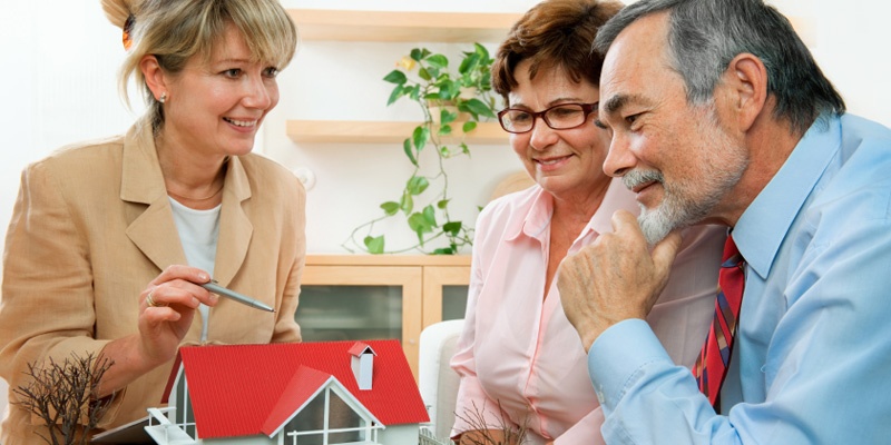 elderly couple looking at model home with loan officer