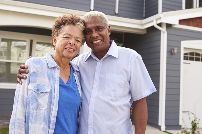 elderly couple smiling standing outside home
