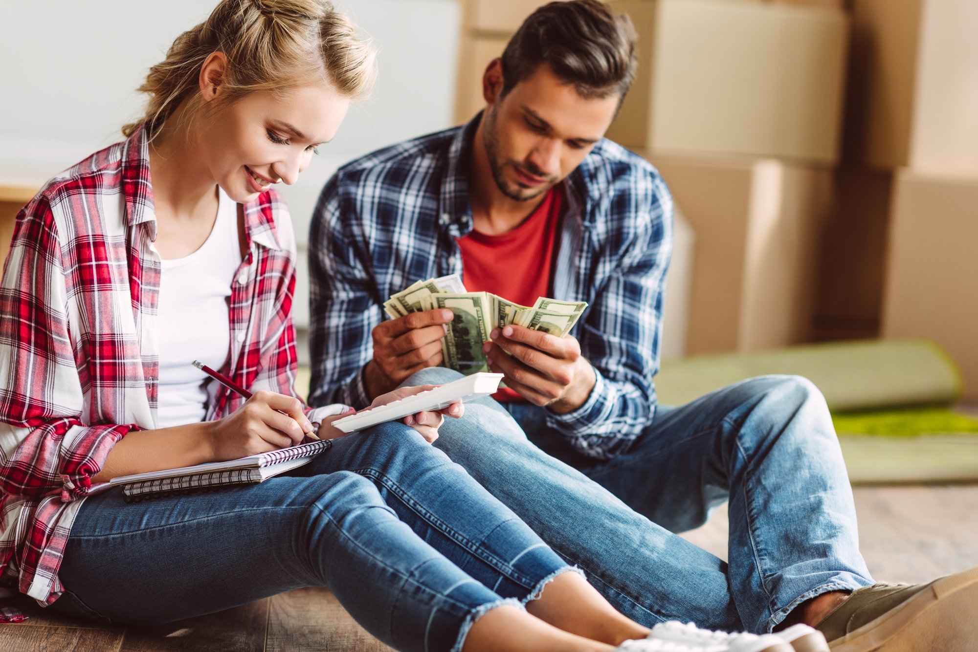 young couple counting money while sitting on floor