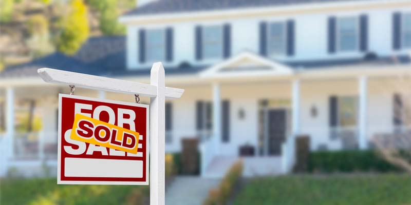 House blurred in background with For Sale sign