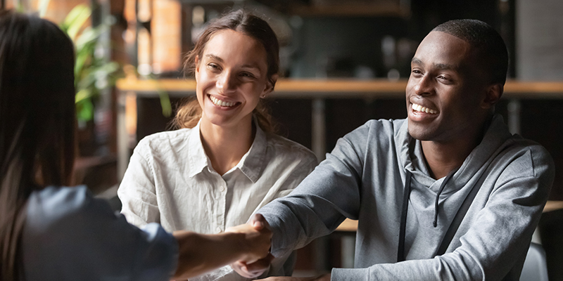 interracial couple shaking hands with a mortgage loan officer