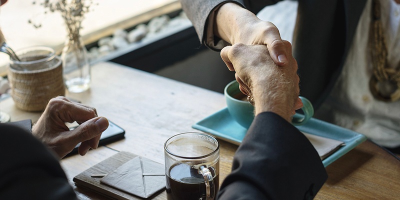 close up of hands shaking at a coffee shop