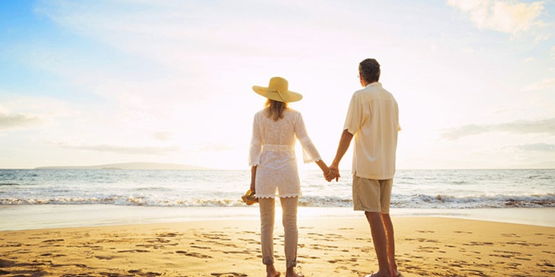 Older couple looking out at horizon and ocean on beautiful beach