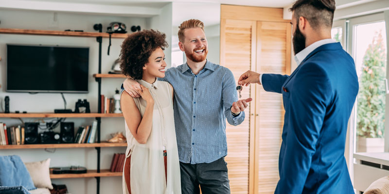 agent handing keys for new home over to couple