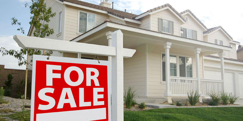 close up shot of a for sale sign in front of a home