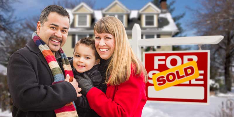 Family in front of For Sale sign
