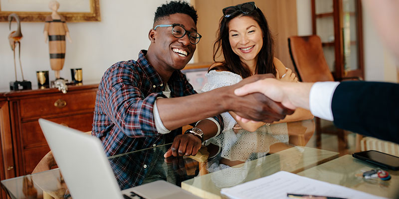 black and asian woman shaking hands on a mortgage agreement