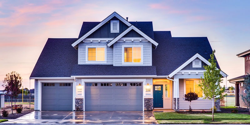 Beautiful home at dusk with lights on in light drizzle