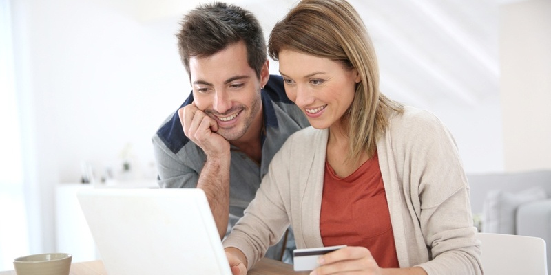 Couple looking at computer and paying