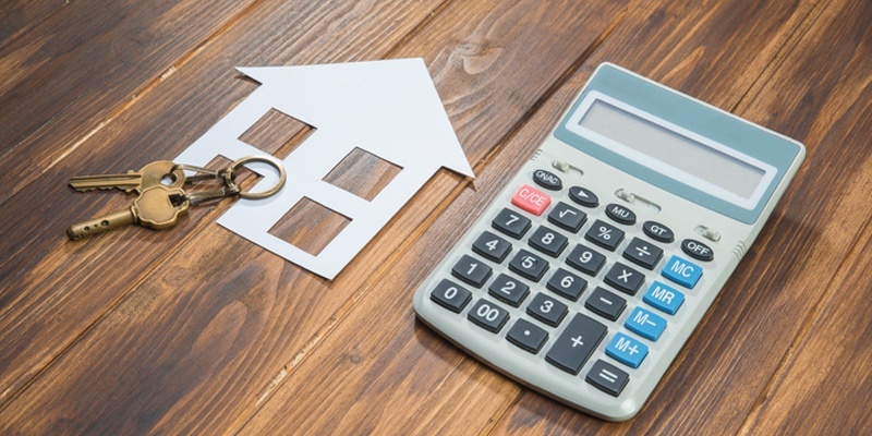 Calculator next to cut out of house symbol with keys