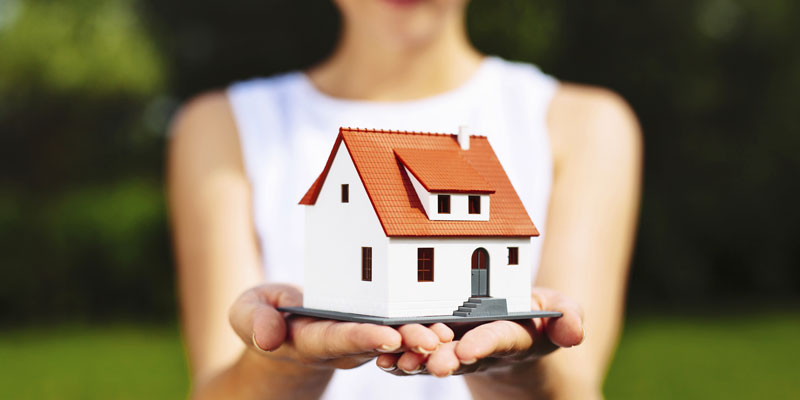 Woman holding small replica of house in both hands